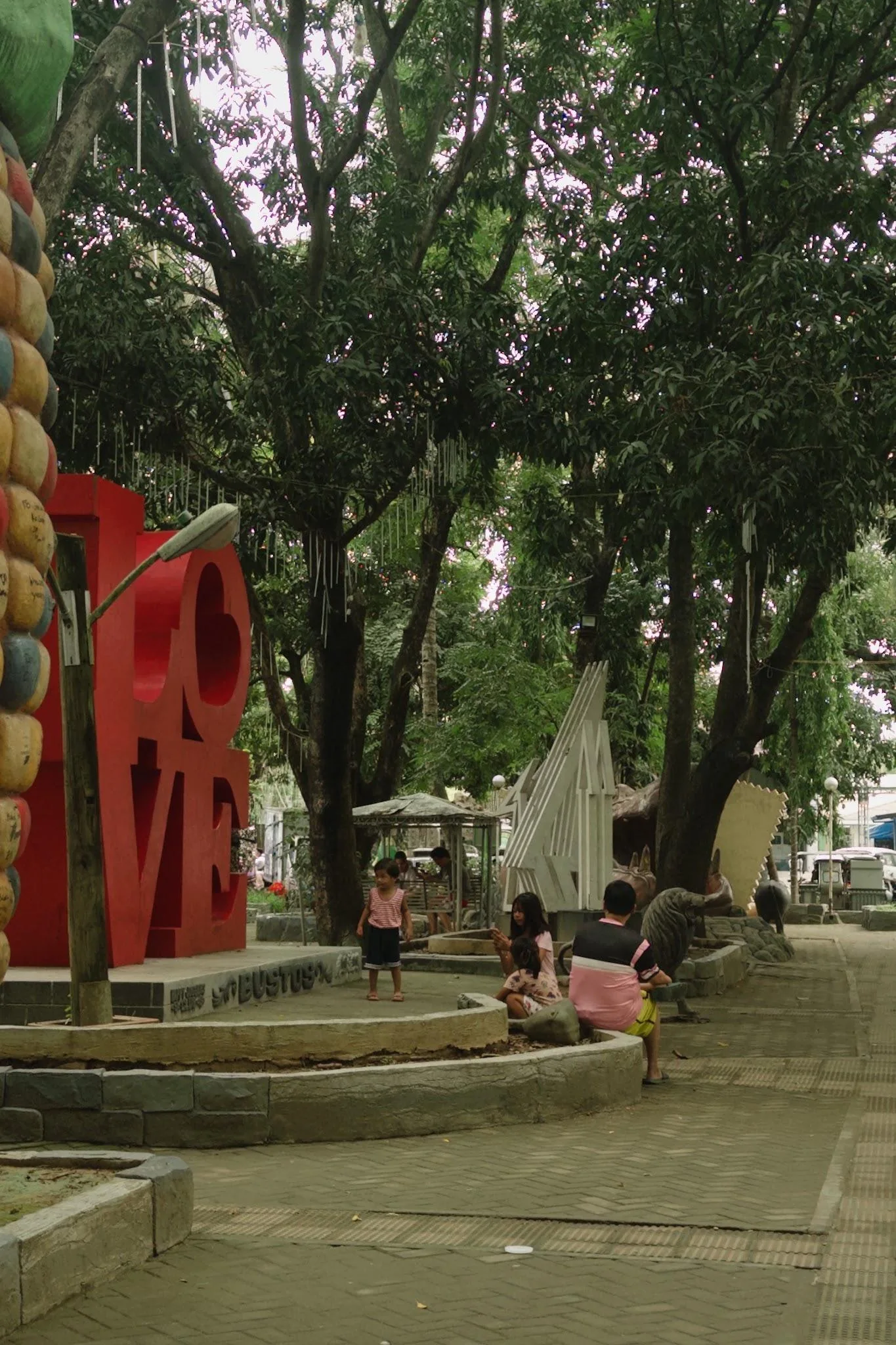 People walking near sculptures and trees inside Bustos Heritage Park