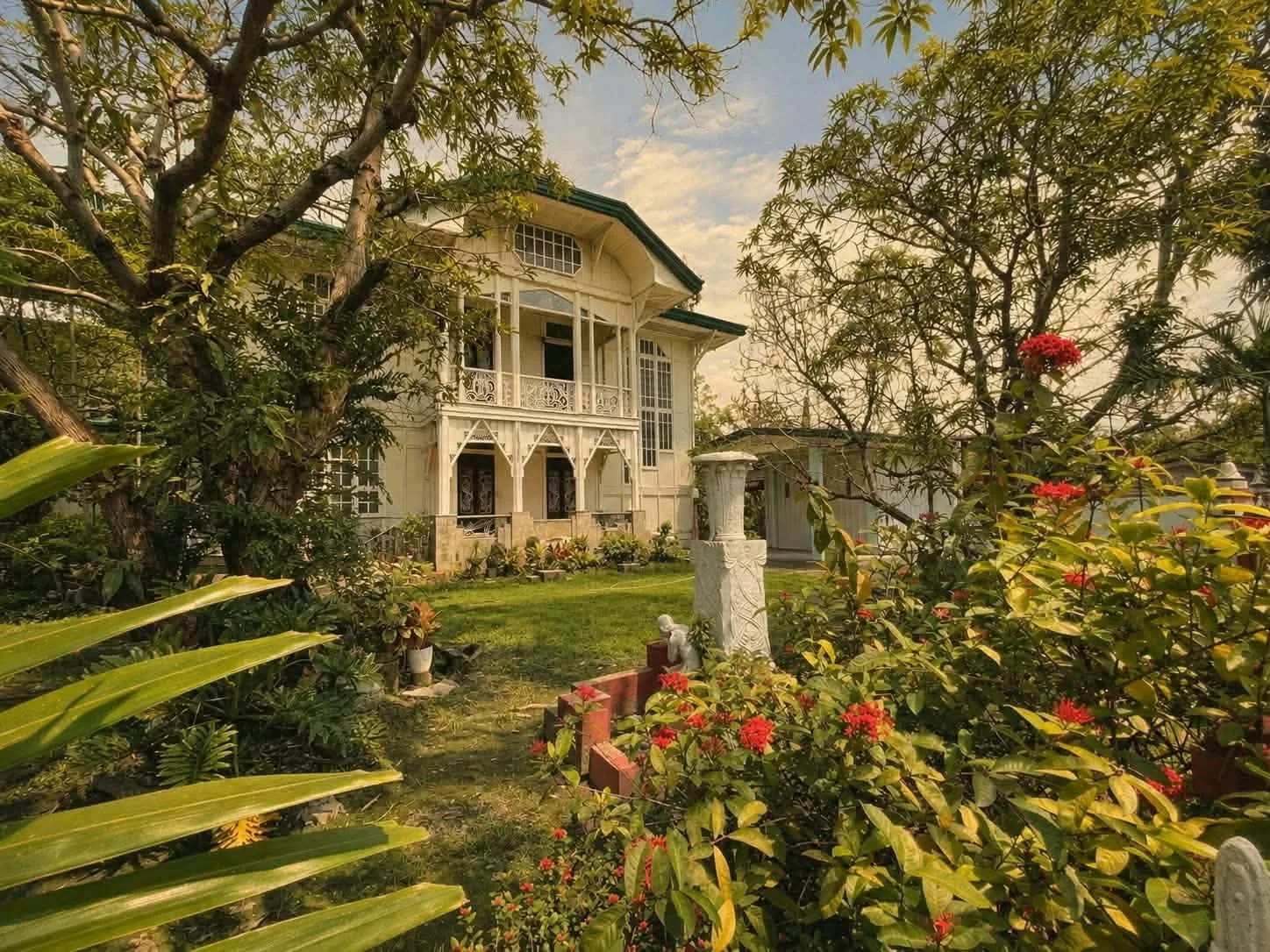 Pale-coloured historic house in a garden with a fountain in Malolos