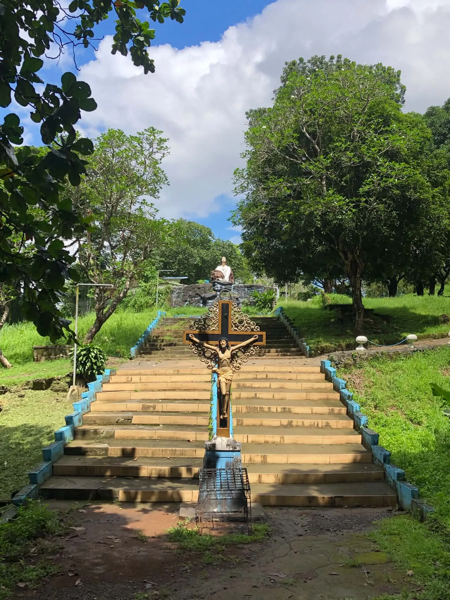 Outdoor steps and a religious cross on a landscaped hill within Lourdes Grotto