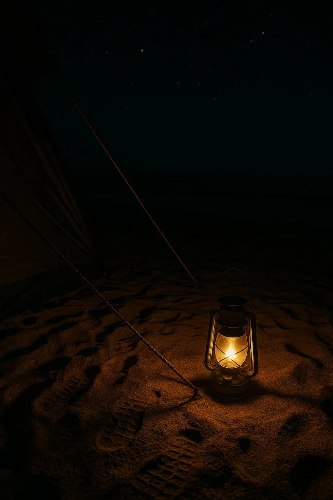 Lantern lighting sand and footprints at night on Luzon beach camping trip