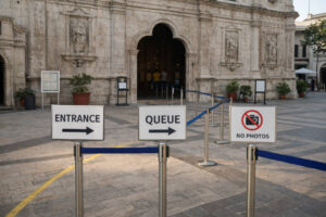 Entrance area of Basilica Minore del Santo Niño with visitors queue and signage