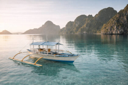 Traditional outrigger boat in Palawan near limestone cliffs for a Palawan island hopping guide