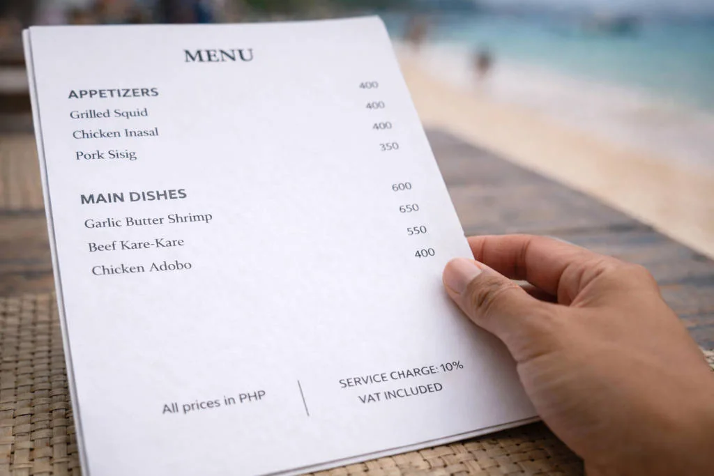 Best Restaurants In Boracay menu close-up showing service charge and VAT included notes