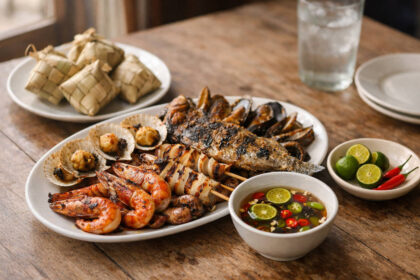 What To Eat In Mactan: A Simple Food Guide For First-Timers Simple table spread showing what to eat in Mactan with grilled seafood, Pusô, and vinegar dip