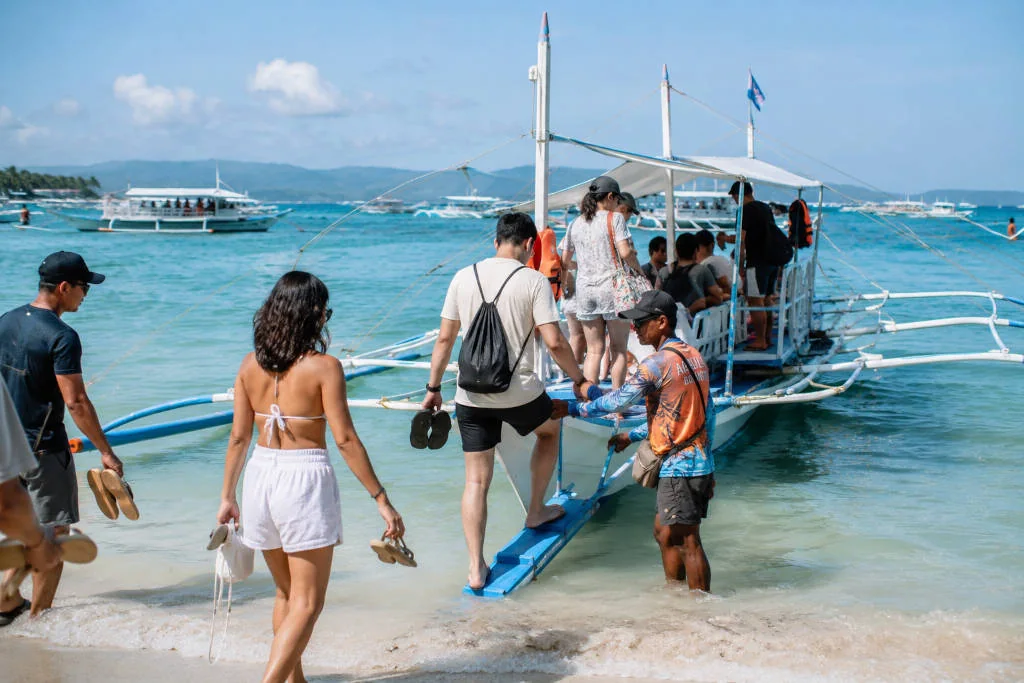 Travelers boarding a boat for a Boracay island hopping tour