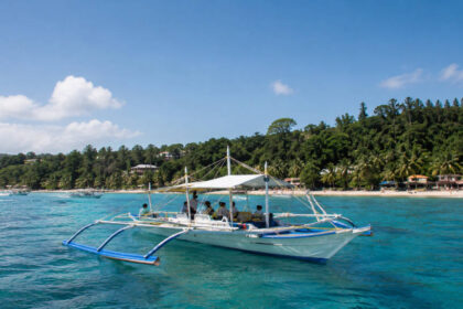 Boracay island hopping boat on calm blue water near the island coastline