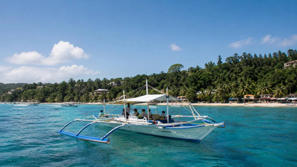 Boracay island hopping boat on calm blue water near the island coastline