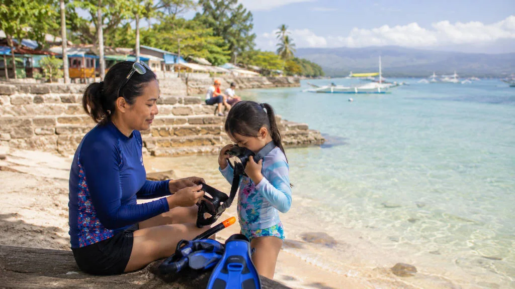 Parent and child preparing for an easy Moalboal with kids snorkeling day